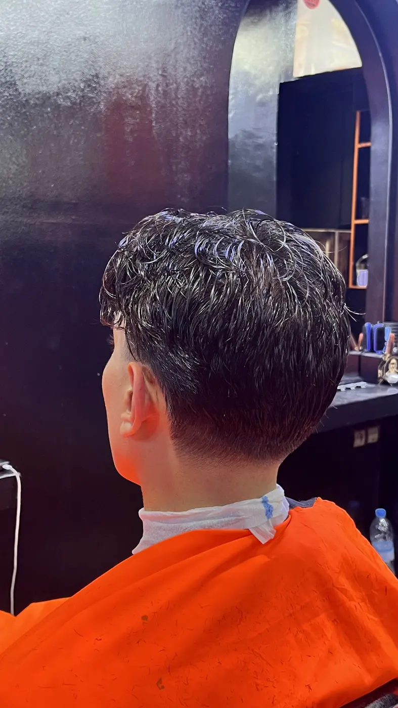 Coupe bouclée avec dégradé, client en cape orange chez PREGA SQUAD